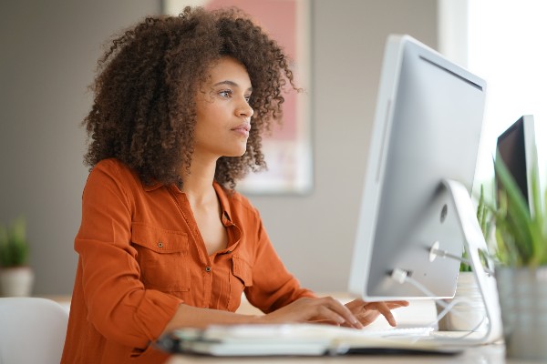 A woman typing on a desktop computer