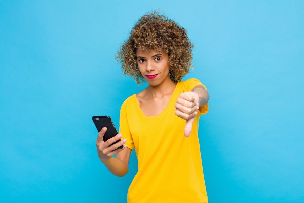 A woman holding a phone with a thumbs down