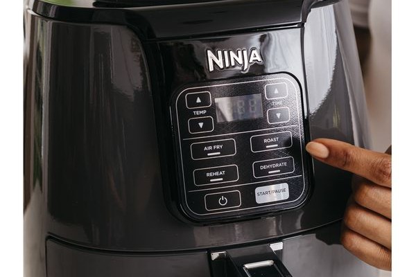 Someone pressing a button on a Ninja Air Fryer